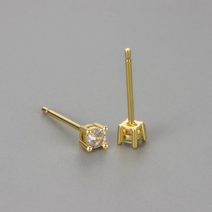 Macro detail of gold-plated four-prong round zircon stud earrings showing fine craftsmanship