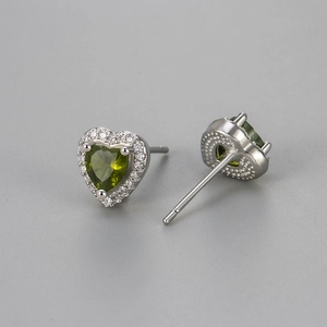 Macro detail of silver heart studs with green zircon stone and pavé crystal border