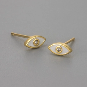 Macro detail of gold evil eye stud earrings with white enamel and sparkling zircon