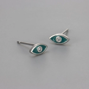 Macro shot of silver evil eye stud earrings with teal enamel and sparkling zircon