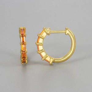 Detail of gold huggie earrings featuring emerald-cut orange cubic zirconia settings