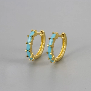 Macro shot of gold hoop earrings featuring rectangular light blue zircon gemstones in a pave setting