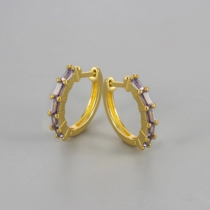 Detailed close-up of golden huggie earrings set with rectangular purple zircon stones
