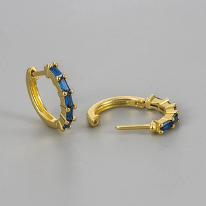Detailed macro view of gold hoop earrings with rectangle-cut deep blue zircon stones