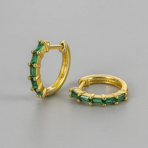 Close-up of golden hoop earrings featuring rectangular green zircon stones in prong setting