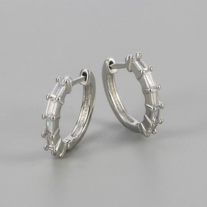 Close-up of silver huggie hoop earrings with baguette-cut sparkling cubic zirconia stones