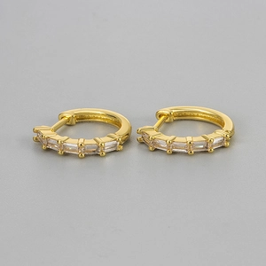 Detailed macro view of golden huggie earrings with five baguette-cut clear zircon stones