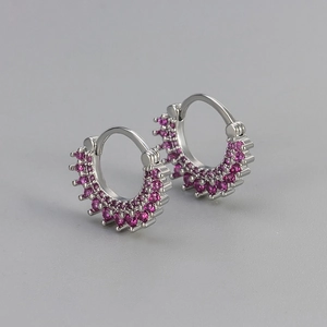 Détail macro de boucles d'oreilles créoles en argent avec zircons roses et serti en couronne