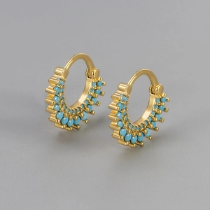 Détail de boucles d'oreilles tournesol dorées avec trois rangées de zircons bleu ciel