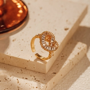Dettaglio di un anello aperto dorato con design intrecciato e zirconi cubici bianchi