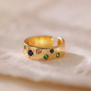 Dettaglio macro dell'anello aperto dorato con zirconi colorati e design vintage