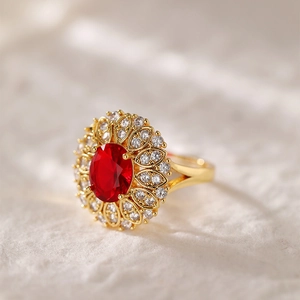 Dettaglio di un anello placcato oro con gemma rossa ovale e zirconi a forma di girasole
