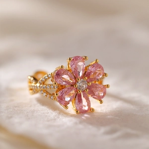 Dettaglio macro dell'anello a fiore dorato con pietre rosa e accenti di zirconi pavè