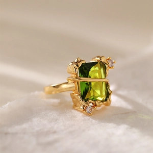 Macro di un anello in oro fuso con una pietra verde oliva rettangolare e zirconi lucidi