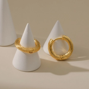 Goldene klobige Creolen mit spiralförmiger Textur auf minimalistischem Display-Ständer