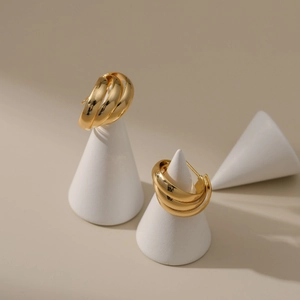 Detalle de pendientes en forma de C bañados en oro de 18K con diseño de triple capa