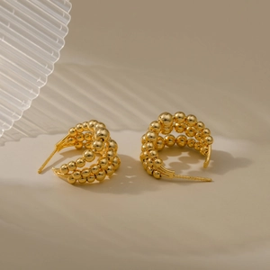 Detalle macro de pendientes en C bañados en oro de 18K con tres filas de cuentas