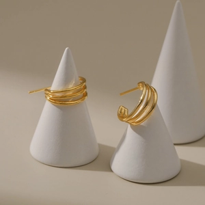 Detalle de pendientes de aro de triple capa bañados en oro de 18K en soporte cónico