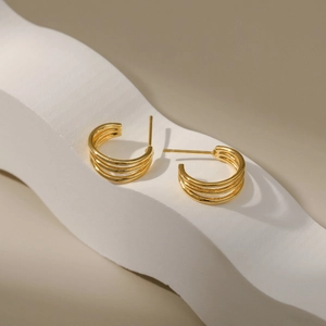 Pendientes de aro multicapa chapados en oro con forma de C en soporte blanco