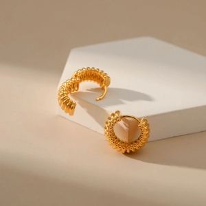18K vergulde oorringen met spiraalvormig ontwerp op een minimalistische witte stand