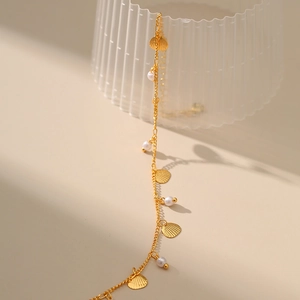 Vista detallada de una tobillera bañada en oro de 18K con conchas y perlas blancas