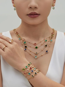 Close-up of colorful round faceted gemstone jewelry set with layered gold chains