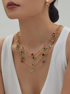 Detailed view of layered gold necklaces featuring multicolored round glass stones on model