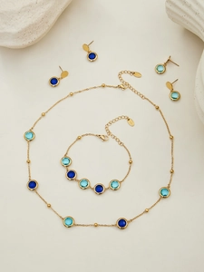 Detail of round cut blue stone jewelry set featuring necklace and bracelet with gold beads