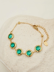 Detailed shot of golden stainless steel bracelet with green faceted glass stones
