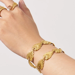 Retro gold leaf chain bracelet and teardrop gemstone ring set on female model's hand