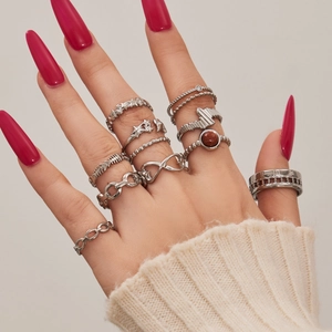 Vintage silver ring set with star and chain designs worn by a model on white background