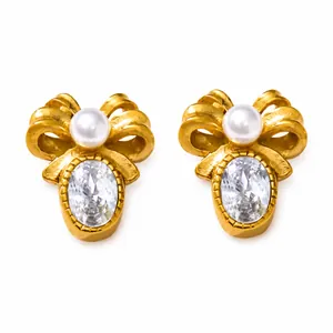 Detail van vintage strikoorbellen met witte parel en ovale edelsteen in mat gouden afwerking