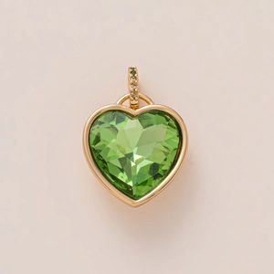 Detailed macro view of heart-shaped gold pendant with a large green gemstone and tiny diamonds