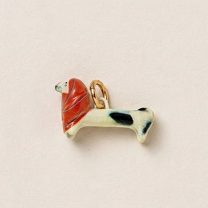 Dettaglio di un ciondolo a forma di cane in ceramica con sciarpa rossa e anello d'oro