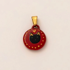 Macro shot of red enamel cat charm with gold heart detail and 18K gold plated loop