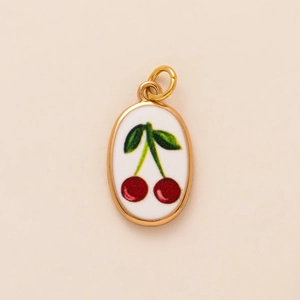 Detail of gold-plated oval pendant featuring hand-painted red cherry and green leaf