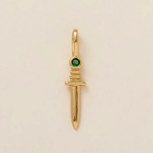 Macro shot of gold dagger pendant featuring a central green gemstone and polished finish