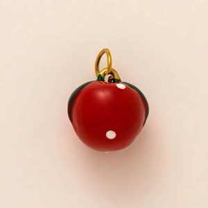 Macro view of a red apple charm with gold ring and white dots for DIY keychains