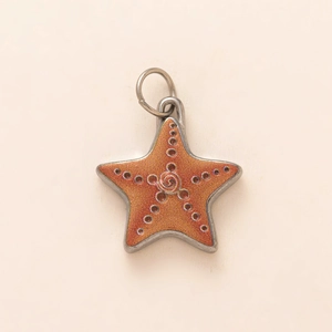 Dettaglio macro del ciondolo a stella marina arancione con finitura glitterata e metallo