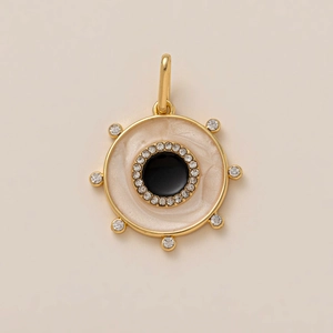Detalle del colgante de sol y timón chapado en oro de 18K con piedra negra y circón