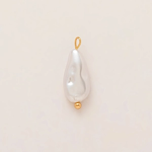 Dettaglio del ciondolo con perla barocca e anello placcato oro 18K su sfondo crema