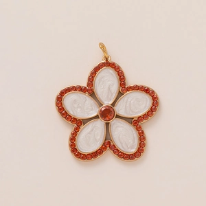Detailed close-up of a flower pendant with white enamel petals and orange crystal inlay