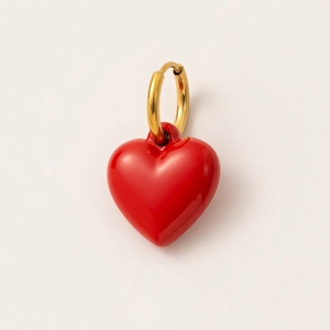 Detalle de un pendiente de aro bañado en oro de 18K con un dije de corazón en esmalte rojo