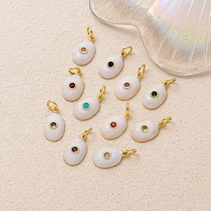 Elegantes colgantes ovalados de esmalte dorado con piedras preciosas sobre fondo beige