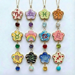 Vue macro de douze pendentifs fleur du zodiaque avec pierres colorées et dorure