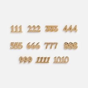 Detalle macro de dijes de números de ángel chapados en oro de 18k del 111 al 999