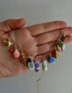 Detail mit verschiedenen Vintage-Anhängern wie goldenen Teekannen und Emaille-Flakons