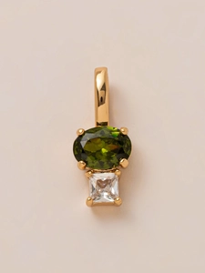Detailopname van vergulde hanger met ovale groene edelsteen en vierkante zirkoon