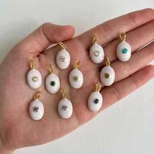 Golden oval enamel pendants with multi-color zircon stones shown in hand for size