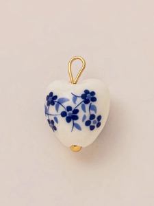 Dettaglio del ciondolo a cuore in ceramica con motivi floreali blu e gancio dorato